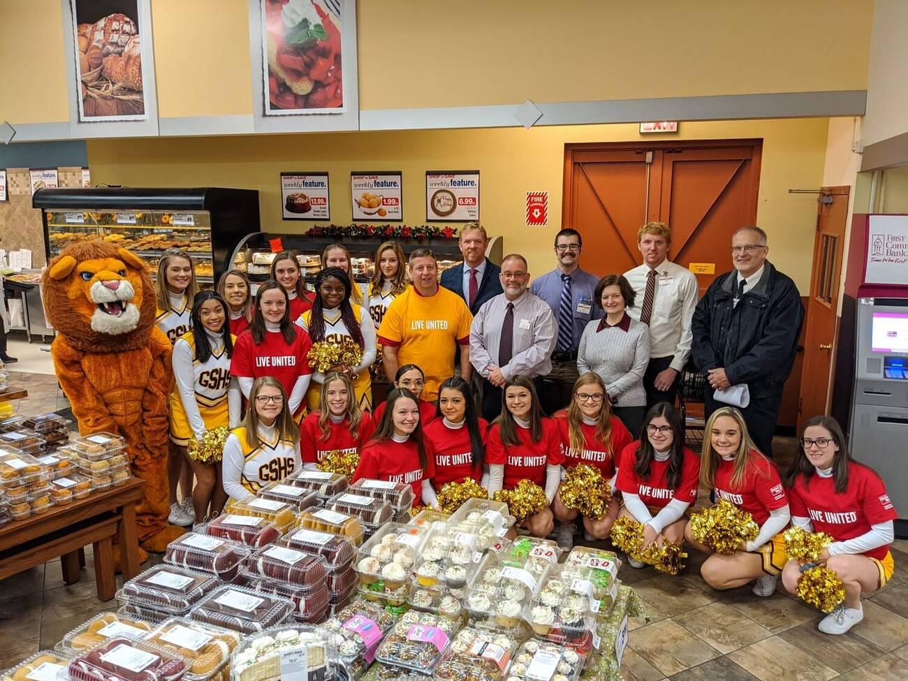 Cheer squad and mascot picking up bakery trays for a school event